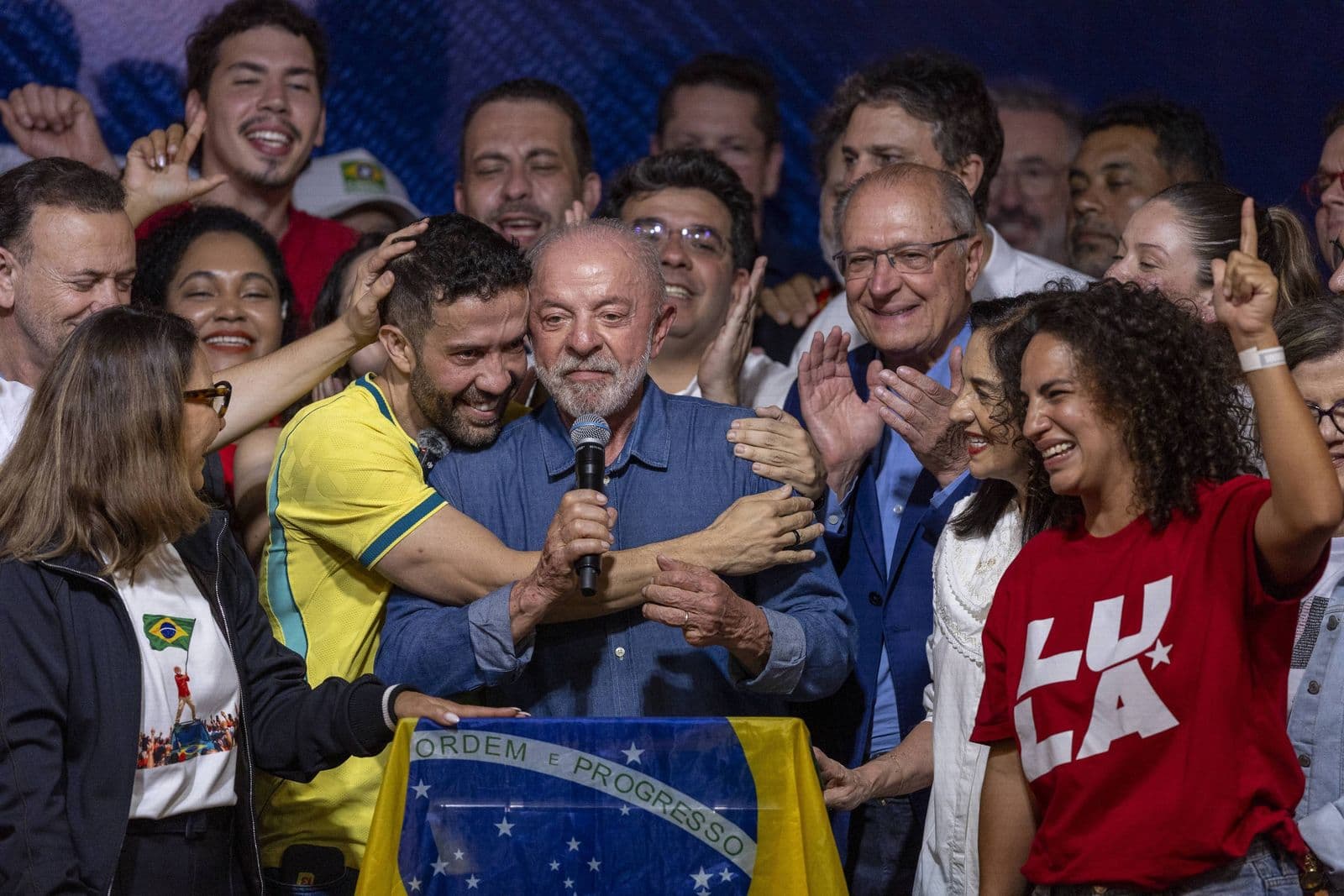 Lula discursa no palco após a vitória nas eleições de 2026, cercado por aliados e políticos jovens