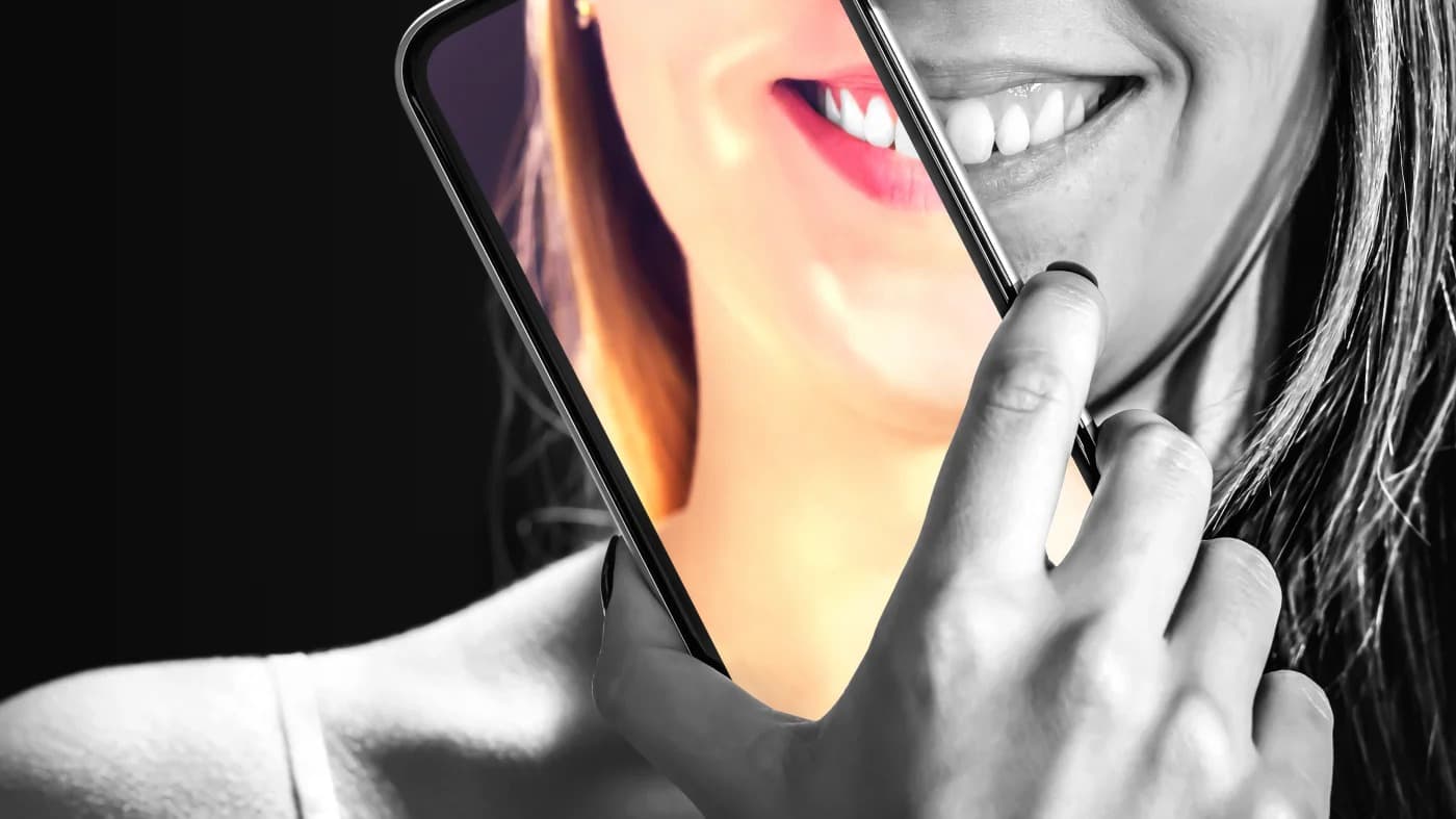 Adolescente observando o próprio rosto em um celular com filtro de beleza aplicado